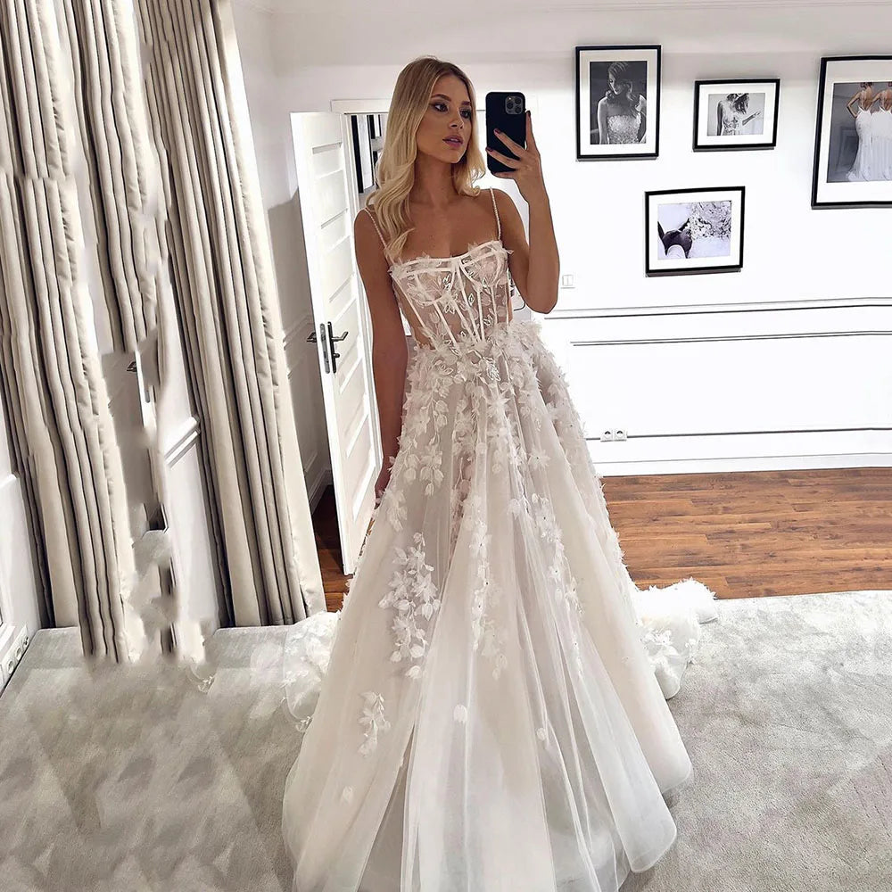 Indulge in pure elegance with our Robe Abrial. This Bohemia wedding dress features delicate 3D flowers, lace appliques, and spaghetti straps for a truly romantic look. Perfect for the modern-day princess bride, this dress will make you feel like royalty on your special day.