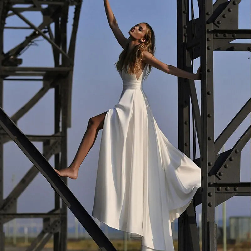 Get ready to stun in the Robe Zenna! This elegant wedding dress features a deep V-neck and backless design, perfect for those who want to make a statement. The spaghetti straps add a touch of delicacy, while the side slit and A-line cut flatter your figure. Feel like a goddess on your special day.