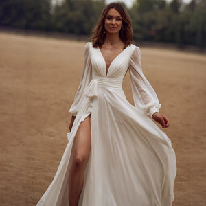Look effortlessly elegant on your special day with our Dress Sidnea. This maxi floor length chiffon wedding dress features long bishop sleeves, a v-neckline, and a backless design for a touch of sophistication. The self-tie sash adds a feminine silhouette while the high cut showcases your figure. Say "I do" in style with this stunning dress.