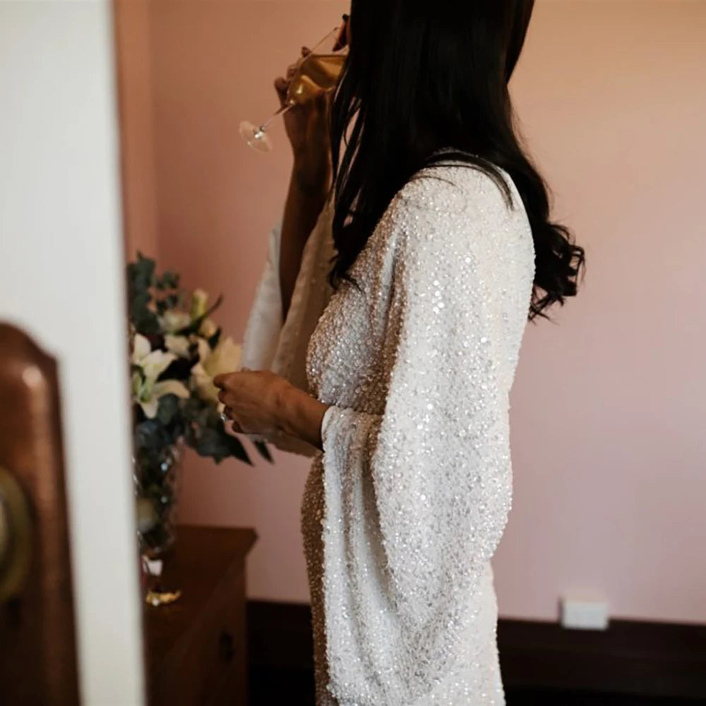 Robe Severine is an exquisite wedding dress tailored to perfection. Richly detailed with lustrious sequined V-neck and long batwing sleeves, it is tailored for an unforgettable bridal gown experience. Its custom-made overweight sizing ensures a comfortable fit and its crystals add a graceful touch to this elegant gown.
