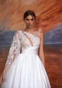 Experience luxurious elegance with our Robe Saira. This exquisite off-shoulder A-line design features playful sleeves and a sexy backless silhouette. Its fluffy texture adds a touch of sophistication to your wedding dress, making you feel confident and glamorous. Elevate your look and make a statement on your special day.