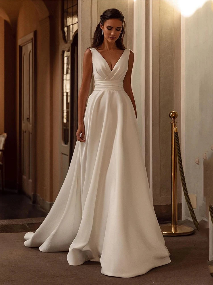 Indulge in the opulent elegance of the Robe Loire. Made with sumptuous satin and featuring a pleated sleeveless design, this V neck bridal dress is perfect for a beach wedding. Its luxurious fabric and sophisticated silhouette will make you feel like the belle of the ball on your special day.