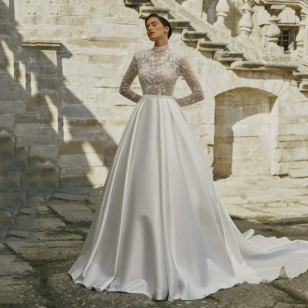 Indulge in timeless elegance with our Robe Prisca. This luxury boho wedding dress features a high neck, long sleeves, and intricate lace and sequin details. Made with satin, it's perfect for a sophisticated bridal look that will make you feel like a work of art.