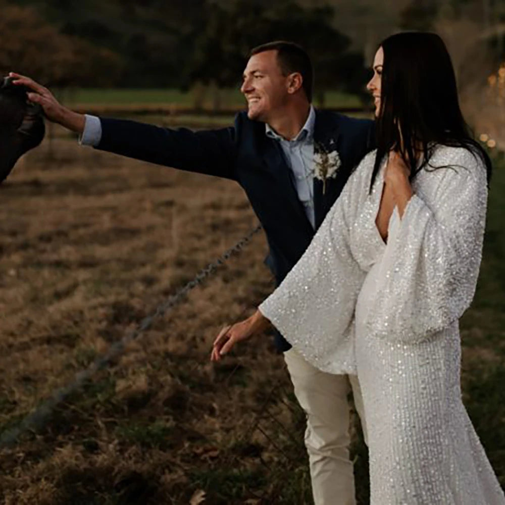 Robe Severine is an exquisite wedding dress tailored to perfection. Richly detailed with lustrious sequined V-neck and long batwing sleeves, it is tailored for an unforgettable bridal gown experience. Its custom-made overweight sizing ensures a comfortable fit and its crystals add a graceful touch to this elegant gown.
