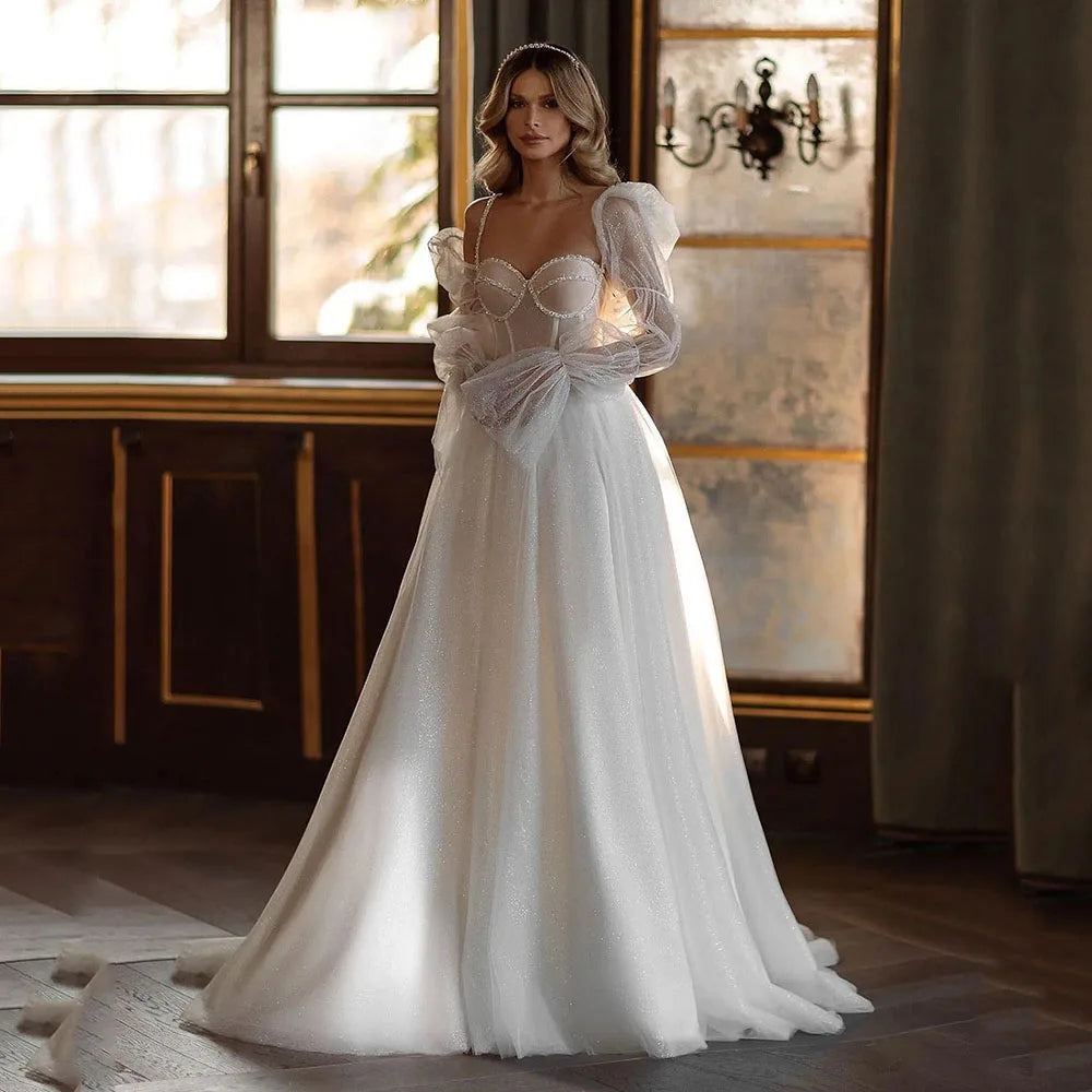 Indulge in the timeless elegance of our Robe Gena. This vintage-inspired wedding dress features a sweetheart neckline, puff sleeves, and a flattering A-line silhouette. Glitter detailing adds a touch of glamour to this sophisticated gown. Make a statement on your special day with this exclusive piece.
