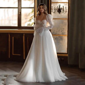 Indulge in the timeless elegance of our Robe Gena. This vintage-inspired wedding dress features a sweetheart neckline, puff sleeves, and a flattering A-line silhouette. Glitter detailing adds a touch of glamour to this sophisticated gown. Make a statement on your special day with this exclusive piece.