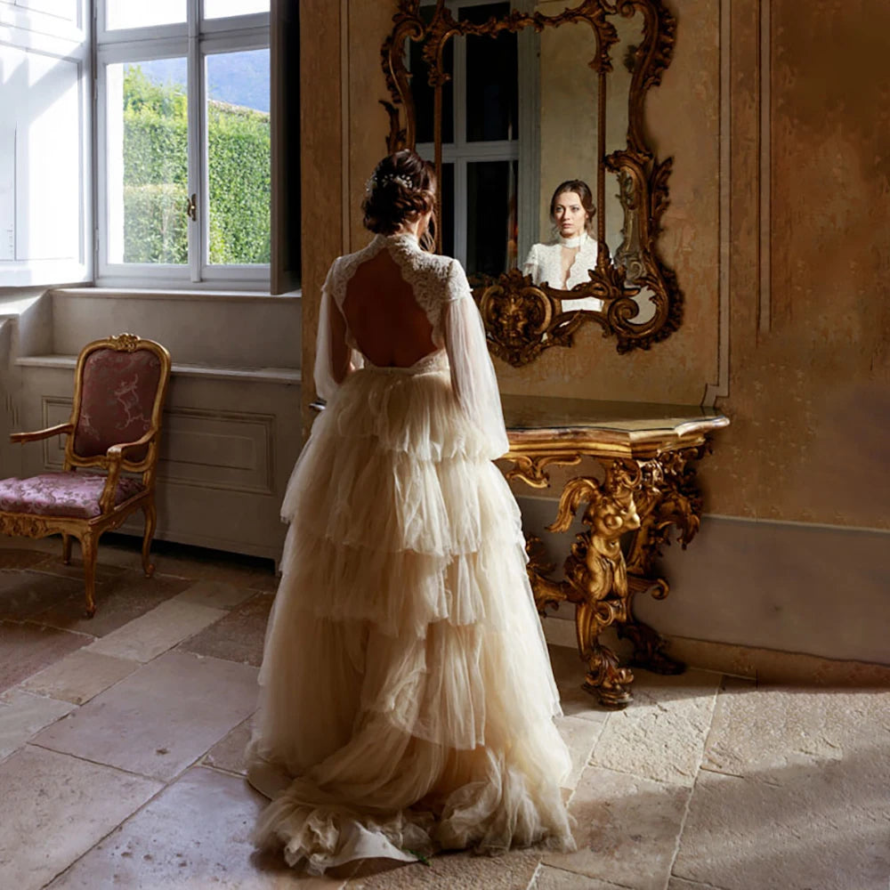 Indulge in sophistication and elegance with our Robe Tali. Featuring long Bishop sleeves, a high neck, and a vintage rustic design, this ball gown is the epitome of luxury. Delicate lace detailing, an open back, and a deep V keyhole add to the allure, making you the center of attention on your special day.