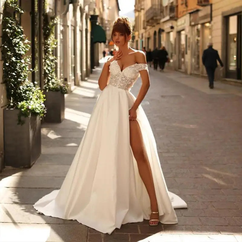 Introducing Dress Eleanor, the ultimate bohemian V-neck wedding dress. With its off the shoulder design, high side slit, and backless style, this dress exudes sexy sophistication. The intricate lace applique and A-line silhouette add a touch of femininity to complete the look. Perfect for the free-spirited bride looking to make a statement on her special day.