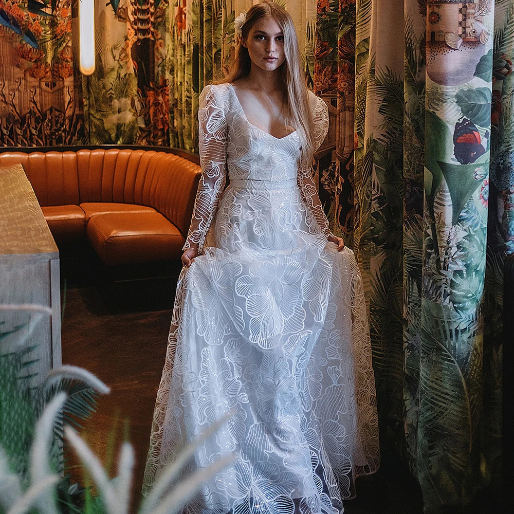 Discover the perfect wedding gown for your special day with Robe Monet's Floral Lace Sequined Square Neck gown. Sheer long sleeves and a low cut two pieces crop top adorn the modern chic look. Plus size design ensures an elegant and stylish fit for every bride. Make your dream come true in this beautiful bridal dress!