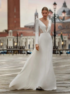Robe Bernadette is the perfect classic wedding dress for your special day. The V-neckline, chapel-length train, full sleeves, and A-line skirt add a timeless elegance to this stunning gown. With the added touch of buttons running down the bodice, you'll be sure to make a lasting impression.