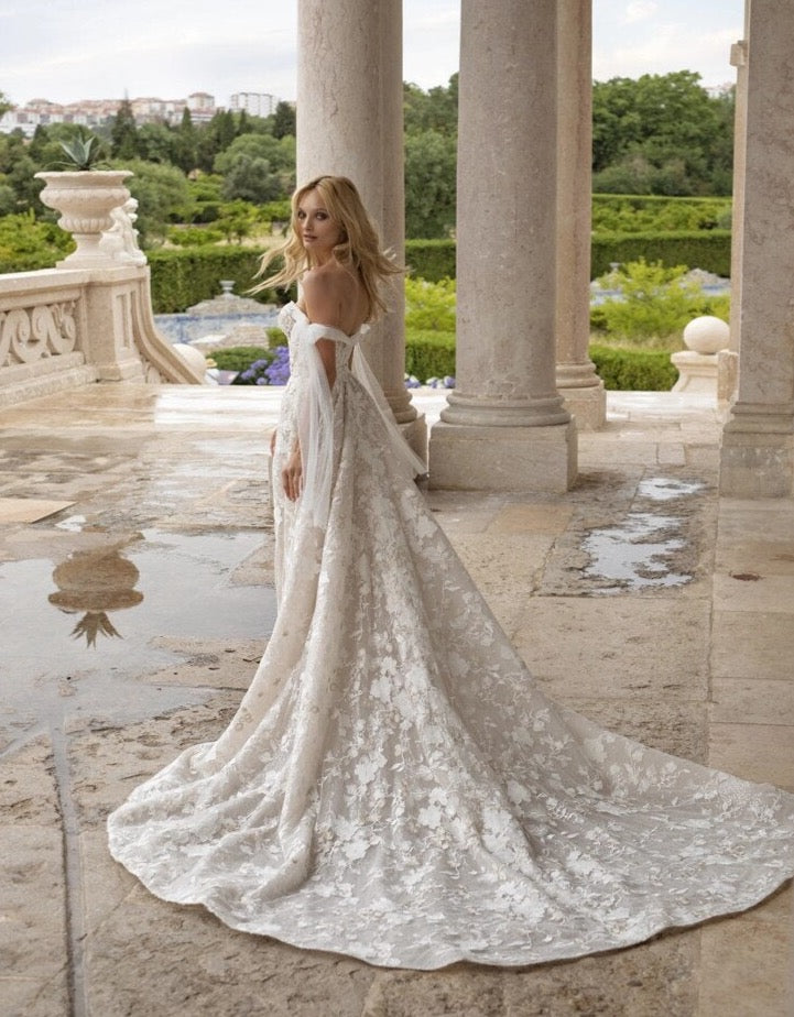 Make your wedding day extra special in our one-of-a-kind Robe Beau! This off-the-shoulder lace beauty will have you feeling like a princess, with its appliqué details, fit for a queen! Lace up your wedding day look with the Robe Beau and make it a moment you'll never forget!
