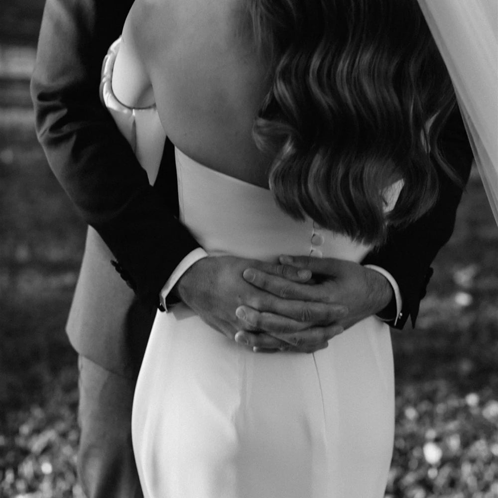 Introducing the Robe Eglantine, a minimalist wedding dress that exudes effortless elegance. This ivory crepe gown features detachable long sleeves for versatility and a sleek sheath silhouette with a brush train for a modern touch. The strapless design and buttons closure add convenience for the bride.