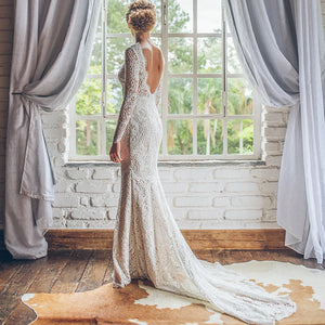 Look breathtaking in the Eleanore, a romantic boho wedding gown crafted in allover lace. Perfect for a graceful mermaid silhouette, this custom-made gown features long sleeves, a boat neckline, and an open back for a truly captivating look. The slim fit flatters the figure, while delicate eyelash lace detailing adds to the classic, yet modern style. An enchanting choice for your special day.