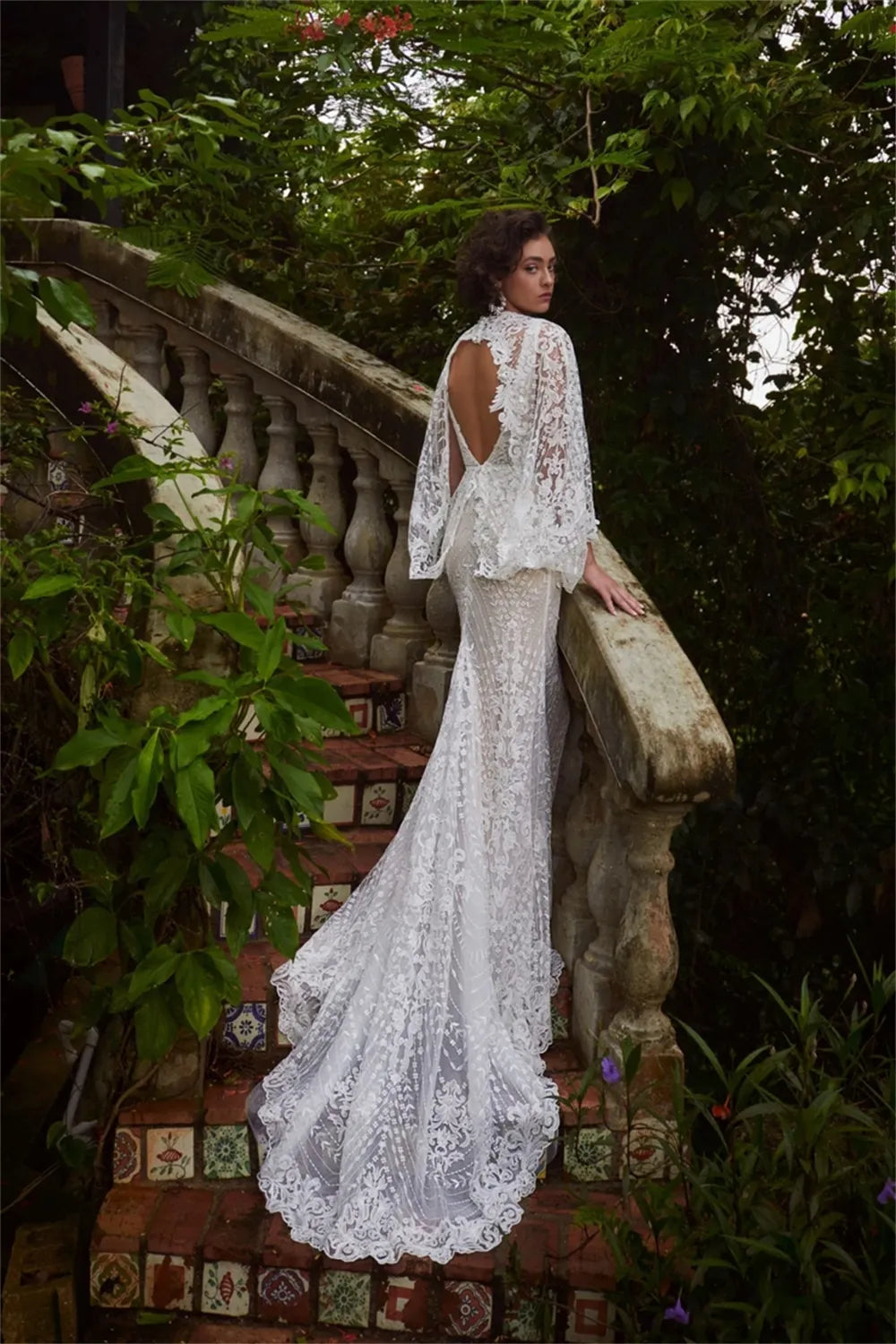 Elevate your special day in the Robe Jacqueline. This exquisite mermaid-style dress is crafted with V-neck and brush floor-length silhouette. Featuring an open back and handmade flower lace accents, this wedding dress is sure to make an unforgettable impression.
