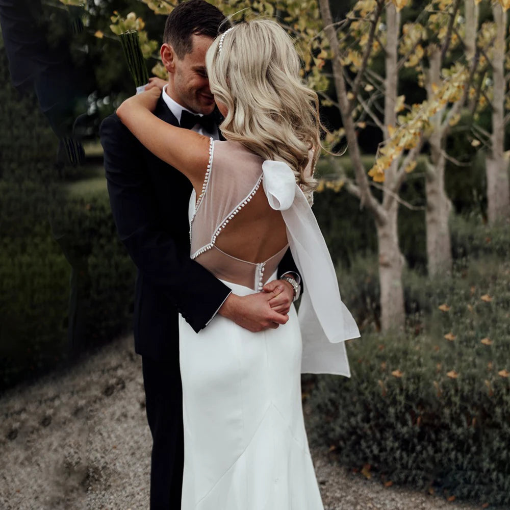 Enjoy a timeless, romantic look in the Marianne robe! Featuring a square neck with crepe illusion tulle and a hollow back sheath, your simple bridal gown will be the star of the show. Plus, you can customize with ribbon and white satin for a truly unique look. High five!