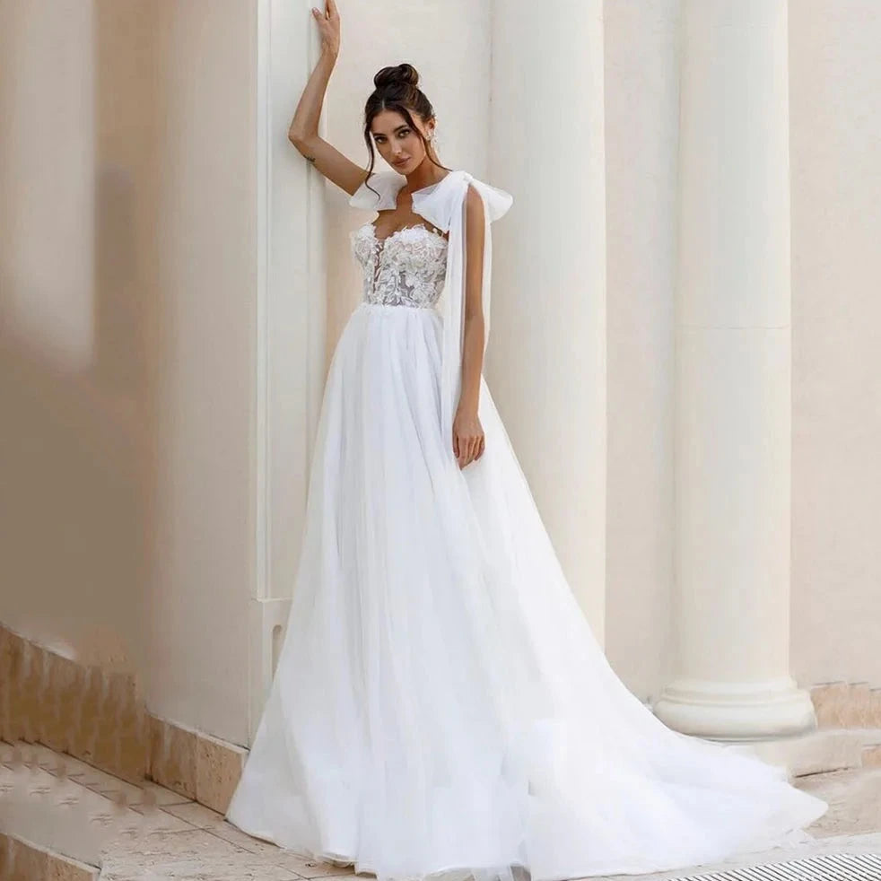 Introducing the Robe Allura - a stunning luxury lace wedding dress with delicate shoulder bows and elegant lace appliques. Designed in a flattering A-line silhouette, this dress is perfect for princess brides with a bohemian touch. Look and feel like a true wedding day princess in this breathtaking gown.