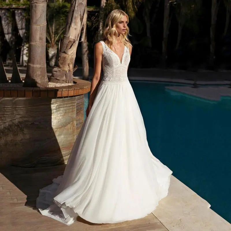 Experience true bohemian style with our Dress Elizabeth. The V-neck and backless design exudes a free-spirited vibe, while the delicate lace applique and flowy chiffon create a romantic and feminine look. Perfect for beach weddings, this sleeveless gown is sure to make you feel like a beautiful bride.