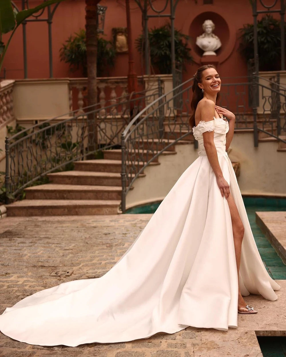 Indulge in luxury and elegance with our Robe Joie. Designed with an off the shoulder neckline, flower details, and soft satin material, this bridal gown exudes sophistication. The side split and corset back add a touch of sensuality, perfect for the modern bride. Elevate your wedding day with this exclusive dress.