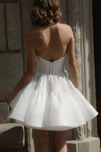 Get ready to stun on your wedding day with the Robe Sherry! This mini wedding dress is perfect for the modern bride, featuring a sweetheart neckline, detachable sleeves, and a boning corset for a flattering fit. Made with luxurious satin, this bridal gown will have you walking down the aisle in style.
