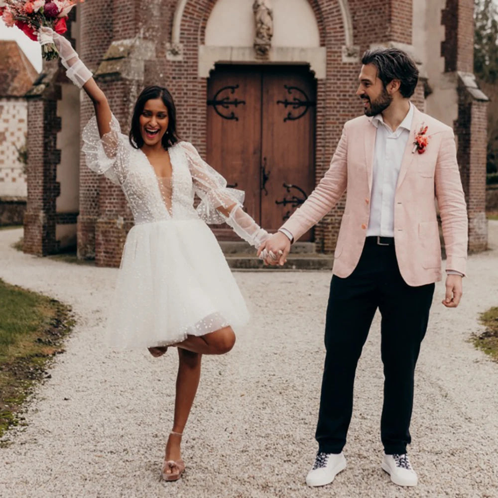 Robe Sidonie is a timeless mini polka dot tulle wedding dress. Featuring a simple V-neck design and an above-knee hem, the dress is finished with ruching details, a low open back, and lantern sleeves. Its classic silhouette is sure to make you the star of your special day.