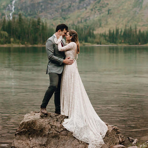 Experience the magic of your special day in our Dress Ava. The boho beach elopement design features long sleeves, a flare backless, and intricate lace with delicate pearls and tassels. The A-line silhouette and V-neckline are complemented by a custom-made belt for a perfect fit. Say "I do" in style with this unique and stunning bridal gown.