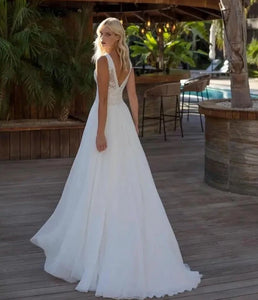 Experience true bohemian style with our Dress Elizabeth. The V-neck and backless design exudes a free-spirited vibe, while the delicate lace applique and flowy chiffon create a romantic and feminine look. Perfect for beach weddings, this sleeveless gown is sure to make you feel like a beautiful bride.