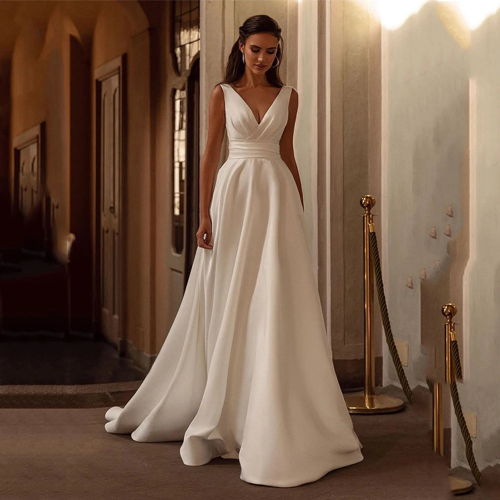 Indulge in the opulent elegance of the Robe Loire. Made with sumptuous satin and featuring a pleated sleeveless design, this V neck bridal dress is perfect for a beach wedding. Its luxurious fabric and sophisticated silhouette will make you feel like the belle of the ball on your special day.