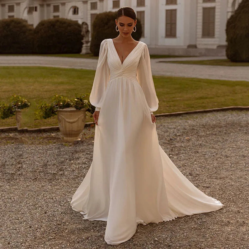 Embrace your inner bohemian goddess with Dress Michelle. The flowy chiffon and long sleeves create a dreamy A-line silhouette, perfect for a custom-made wedding dress. Add a touch of whimsy with the sweep train, making you feel like a true boho bride. Let your free-spirited style shine on your special day.