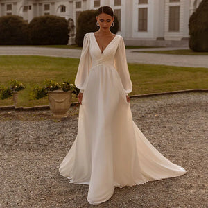 Embrace your inner bohemian goddess with Dress Michelle. The flowy chiffon and long sleeves create a dreamy A-line silhouette, perfect for a custom-made wedding dress. Add a touch of whimsy with the sweep train, making you feel like a true boho bride. Let your free-spirited style shine on your special day.