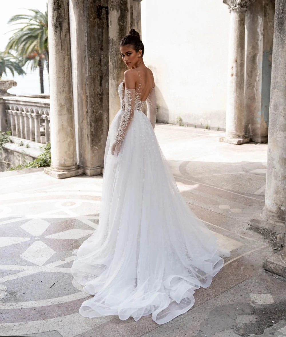 Unleash your inner boho goddess with our Robe Linnet! This stunning V-neck wedding gown features delicate dotted tulle, detachable sleeves, and ruched details for a dreamy, ethereal look. Perfect for the free-spirited bride who loves a touch of whimsy on her special day. Say 'I do' to the Robe Linnet!