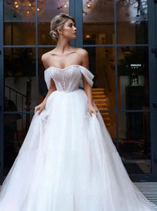 Elevate your wedding day look with our Robe Melina. This elegant ball gown boasts intricate beading, an off the shoulder sweetheart neckline, and a sleeveless tulle design. Perfect for the sophisticated bride seeking a touch of luxury and glamour.