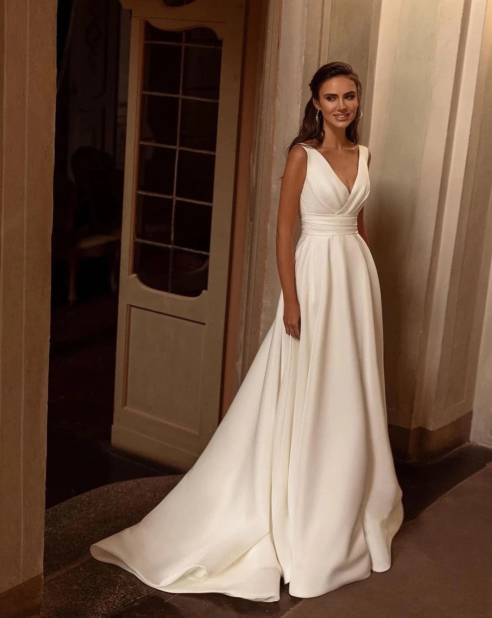 Indulge in the opulent elegance of the Robe Loire. Made with sumptuous satin and featuring a pleated sleeveless design, this V neck bridal dress is perfect for a beach wedding. Its luxurious fabric and sophisticated silhouette will make you feel like the belle of the ball on your special day.