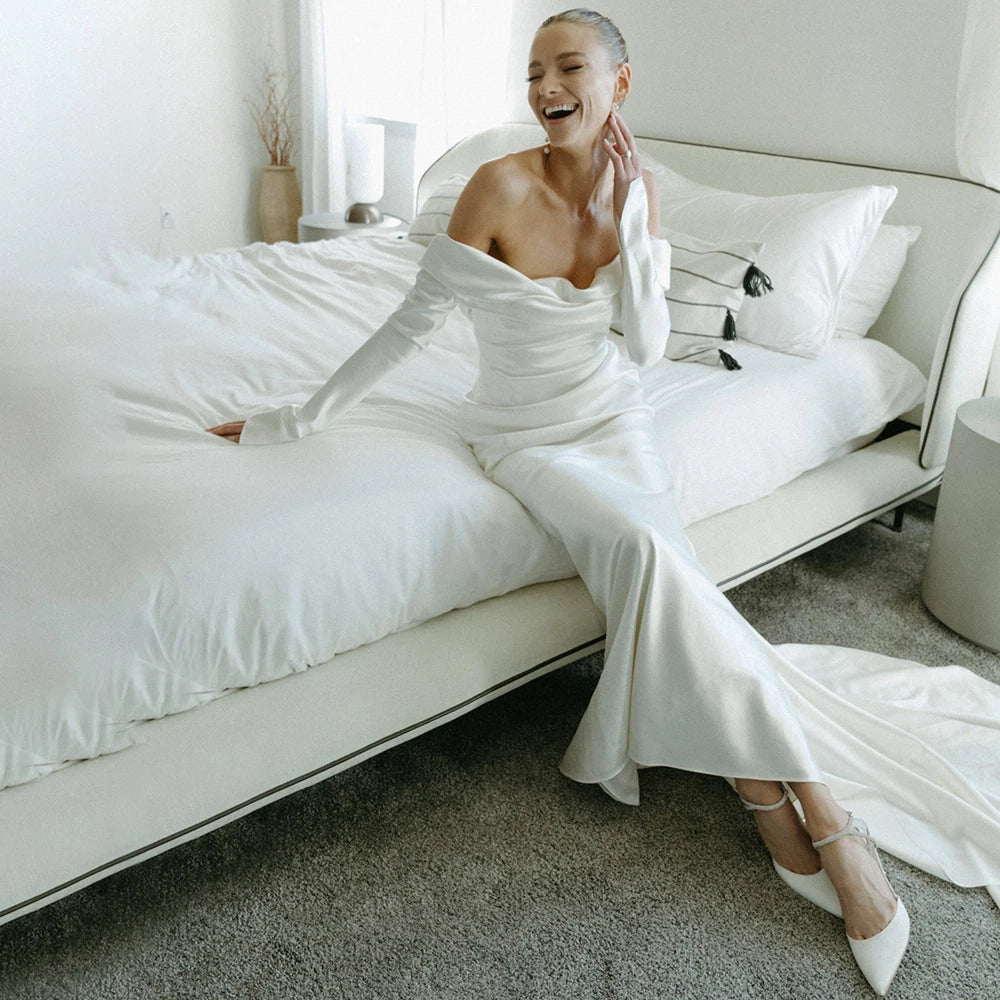 Introducing the Robe Rochelle - the perfect blend of sleek and elegant. With its long sleeves and dropped off shoulder design, this satin wedding dress exudes a simple yet glamorous vibe. Custom made to ensure a glossy finish, this dress is bound to make you shine on your special day.