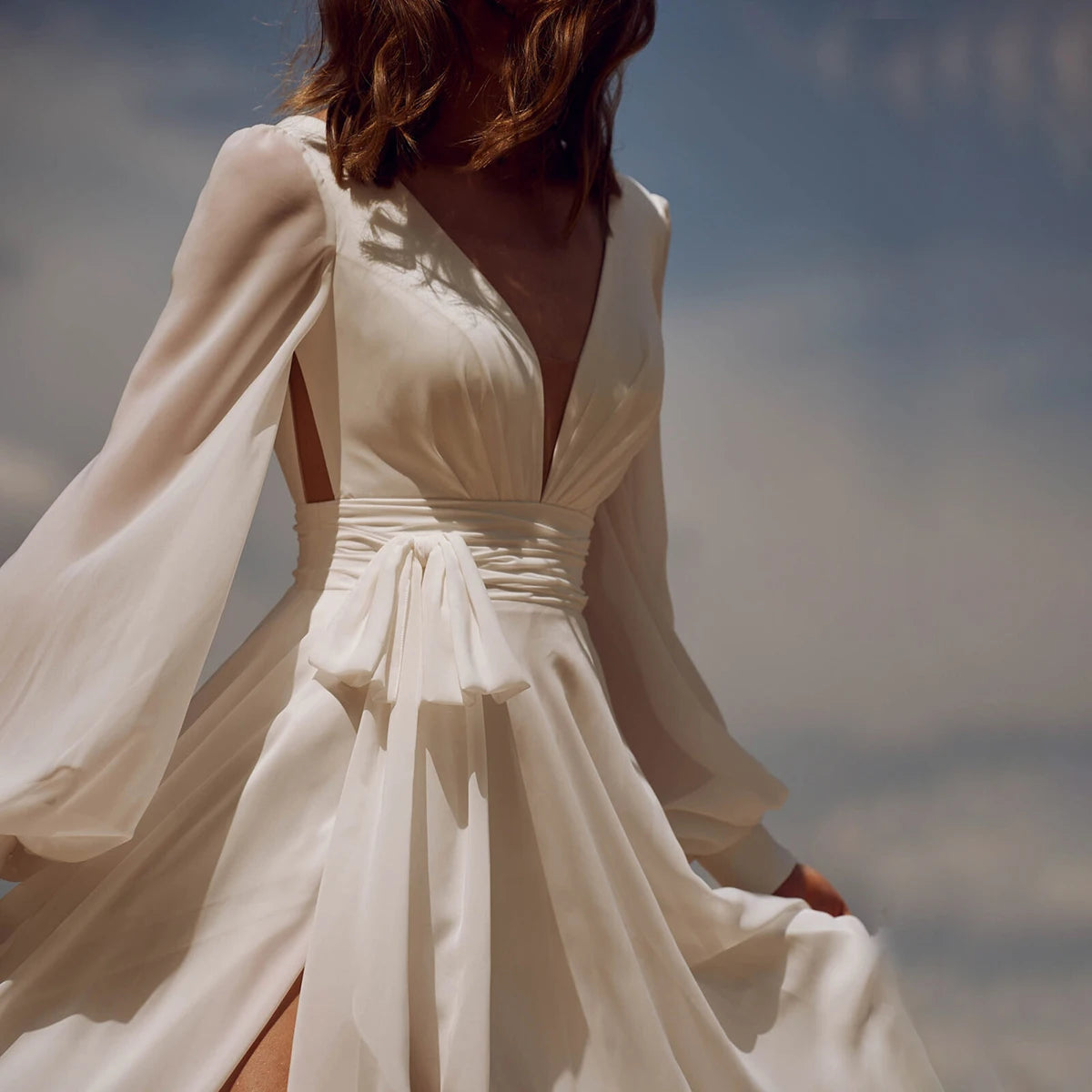 Look effortlessly elegant on your special day with our Dress Sidnea. This maxi floor length chiffon wedding dress features long bishop sleeves, a v-neckline, and a backless design for a touch of sophistication. The self-tie sash adds a feminine silhouette while the high cut showcases your figure. Say "I do" in style with this stunning dress.