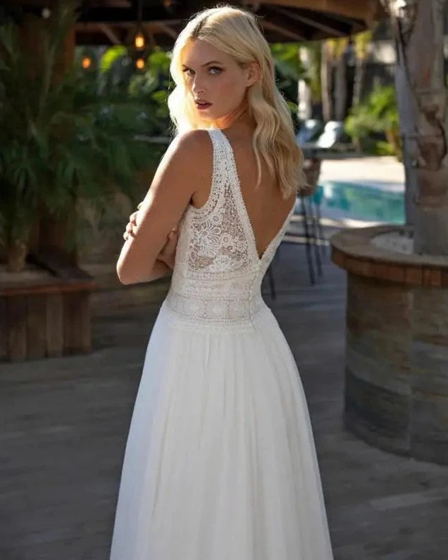 Experience true bohemian style with our Dress Elizabeth. The V-neck and backless design exudes a free-spirited vibe, while the delicate lace applique and flowy chiffon create a romantic and feminine look. Perfect for beach weddings, this sleeveless gown is sure to make you feel like a beautiful bride.