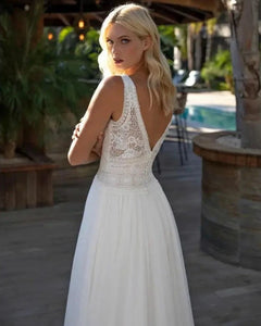 Experience true bohemian style with our Dress Elizabeth. The V-neck and backless design exudes a free-spirited vibe, while the delicate lace applique and flowy chiffon create a romantic and feminine look. Perfect for beach weddings, this sleeveless gown is sure to make you feel like a beautiful bride.