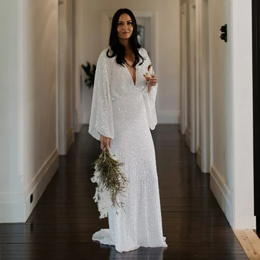 Robe Severine is an exquisite wedding dress tailored to perfection. Richly detailed with lustrious sequined V-neck and long batwing sleeves, it is tailored for an unforgettable bridal gown experience. Its custom-made overweight sizing ensures a comfortable fit and its crystals add a graceful touch to this elegant gown.