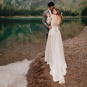 Experience the magic of your special day in our Dress Ava. The boho beach elopement design features long sleeves, a flare backless, and intricate lace with delicate pearls and tassels. The A-line silhouette and V-neckline are complemented by a custom-made belt for a perfect fit. Say "I do" in style with this unique and stunning bridal gown.