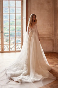 Elevate your wedding day look with our Dress Chantalle! Featuring a classic A-line silhouette, scoop neckline, and detachable cape sleeves, this dress is the epitome of elegance. Delicate appliques lace and a sophisticated train add romantic details to this modern bride gown. Make your special day unforgettable with Robe Chantalle.