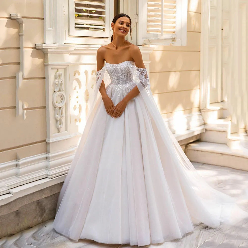 Indulge in pure luxury with the Robe Amia. This elegant off the shoulder A-line wedding dress boasts a sleeveless design that exudes sophistication. Adorned with vintage sequin lace applique and delicate tulle, this bridal gown is a work of art. Make a statement on your special day with the Robe Amia.
