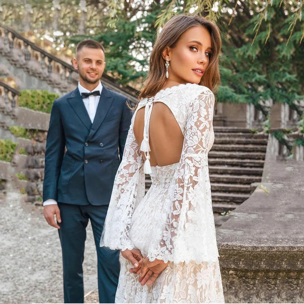 Indulge in luxury with our Dress Arabelle. Showcasing delicate scalloped lace and a plunging v-neck, this wedding dress is customizable with long bell sleeves and tassled ties at the back for a bohemian touch. Cutouts add a modern twist to this timeless piece. Perfect for the sophisticated and fashionable bride.