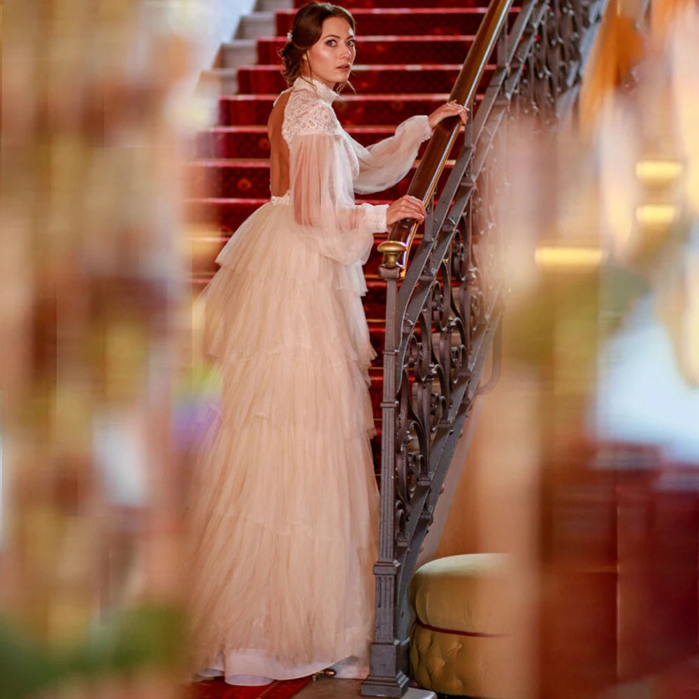 Indulge in sophistication and elegance with our Robe Tali. Featuring long Bishop sleeves, a high neck, and a vintage rustic design, this ball gown is the epitome of luxury. Delicate lace detailing, an open back, and a deep V keyhole add to the allure, making you the center of attention on your special day.