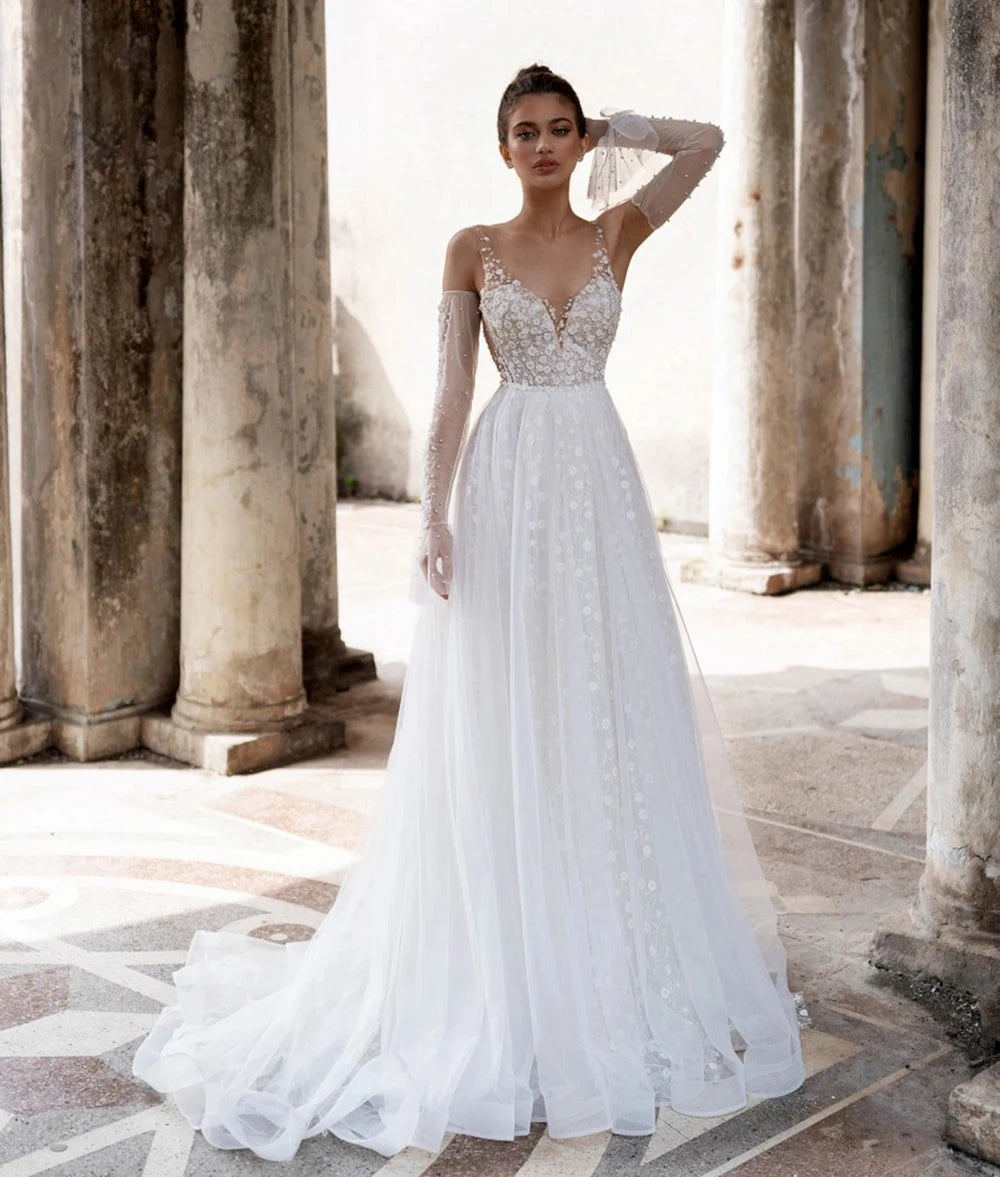 Unleash your inner boho goddess with our Robe Linnet! This stunning V-neck wedding gown features delicate dotted tulle, detachable sleeves, and ruched details for a dreamy, ethereal look. Perfect for the free-spirited bride who loves a touch of whimsy on her special day. Say 'I do' to the Robe Linnet!
