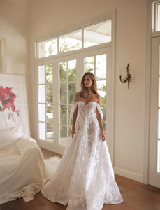 Introducing the Robe Romany, a stunning wedding dress that exudes elegance and sophistication. With its off-shoulder design and A-line silhouette, this dress is perfect for any bride looking to make a statement on their special day. Its luxurious look and feel will make you feel like a true queen on your wedding day.