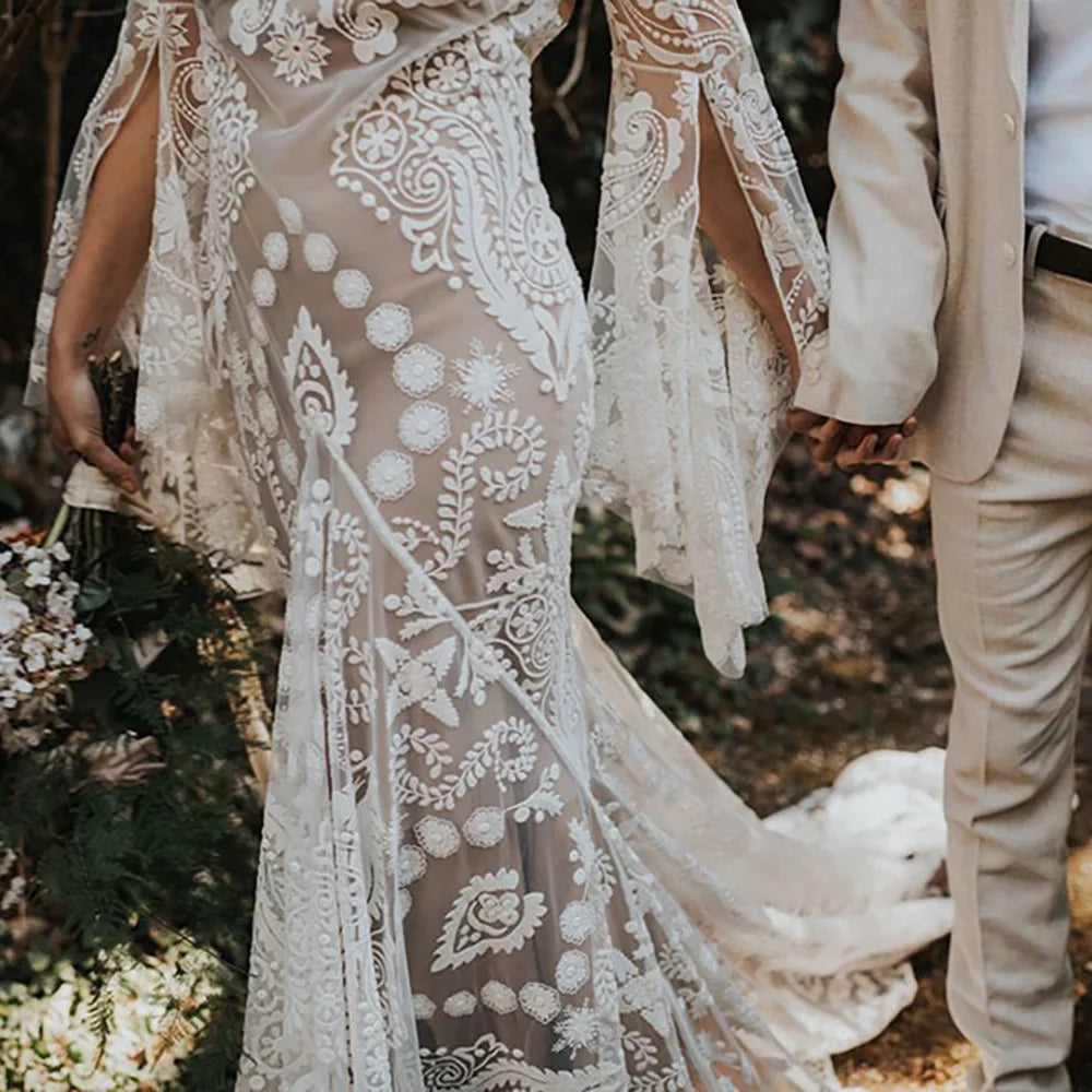 Expertly crafted for the modern and elegant bride, the Robe Anaise features delicate lace detailing and a sleek, form-fitting silhouette. Its long batwing sleeves and high neck add a touch of bohemian flair, while the custom made double slip with slit ensures comfort and movement on the big day. Complete your bridal look with this two-piece, backless sheath gown.
