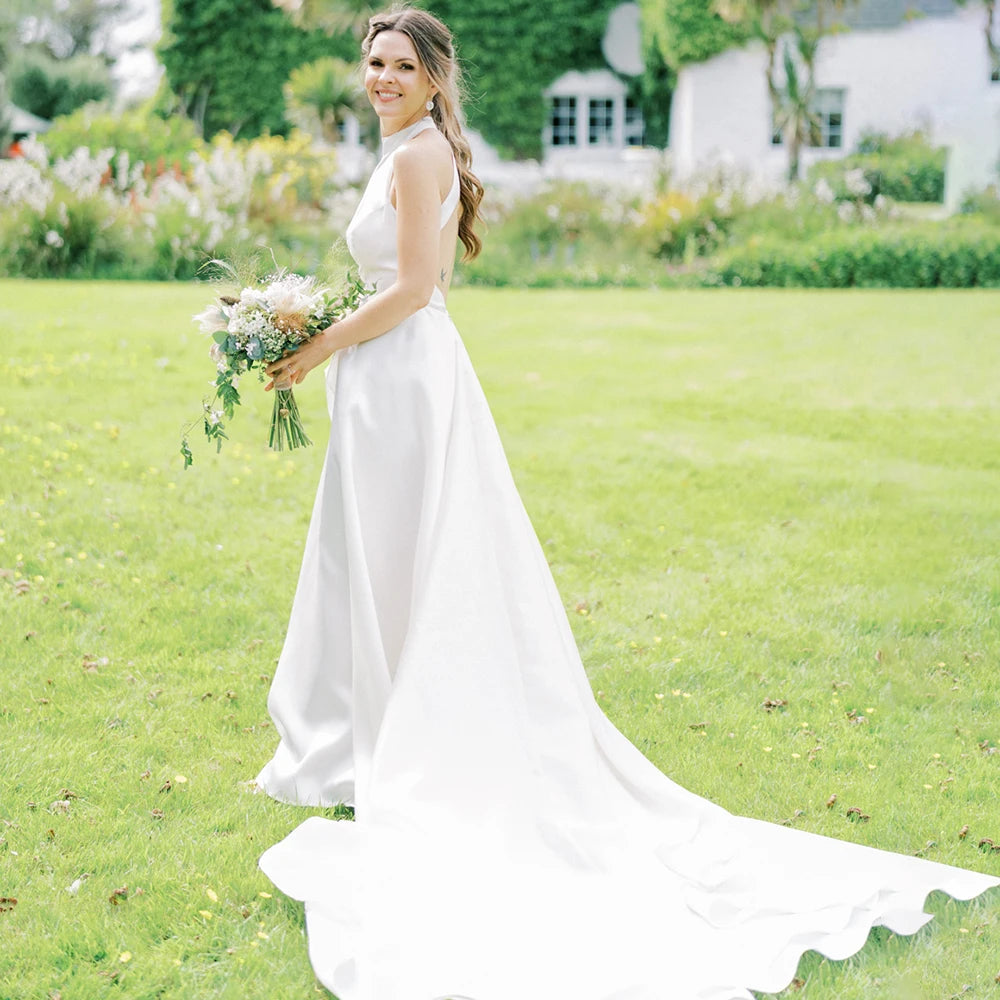 Introducing Robe Morgana, the perfect wedding dress for brides seeking a simple, timeless look. Our custom-made A-line silhouette features a cold-shoulder ruffle trim, satin open back, and round halter neckline. Let your unique beauty shine through on your big day with minimalistic elegance.