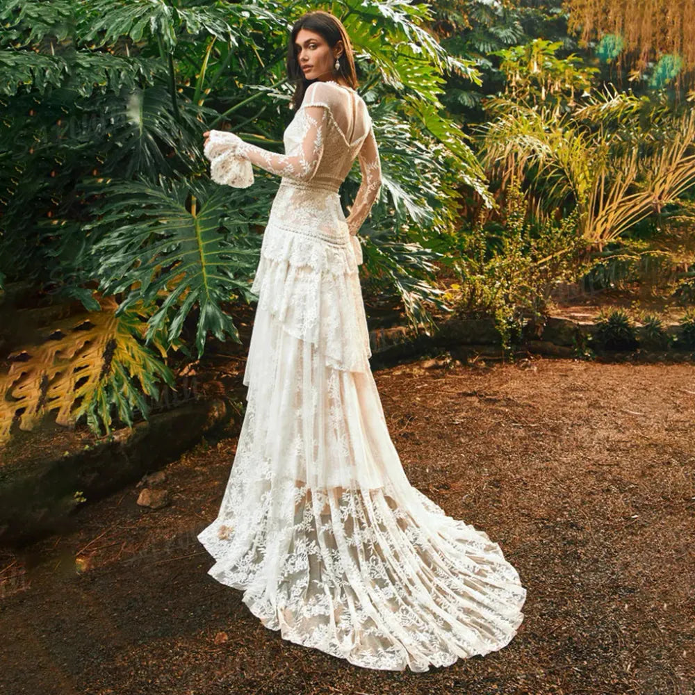 The Mila Dress is a one-of-a-kind Bohemian Lace Tulle Wedding Dress, perfect for the free-spirited bride. Made with custom tiers and long lace sleeves, this A-line dress features a backless design for a stunning and unique look. Step down the aisle in style with this beautiful and elegant bridal gown.