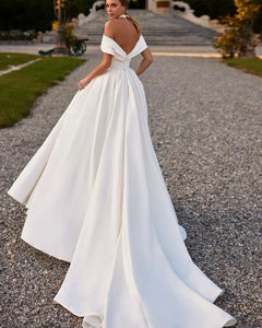 Indulge in luxury on your special day with the Robe Lotta. Featuring an elegant white A-line design and an off-the-shoulder neckline, this wedding dress is made of smooth satin for a sophisticated look and feel. Make a statement that exudes grace and refinement with this exclusive piece.
