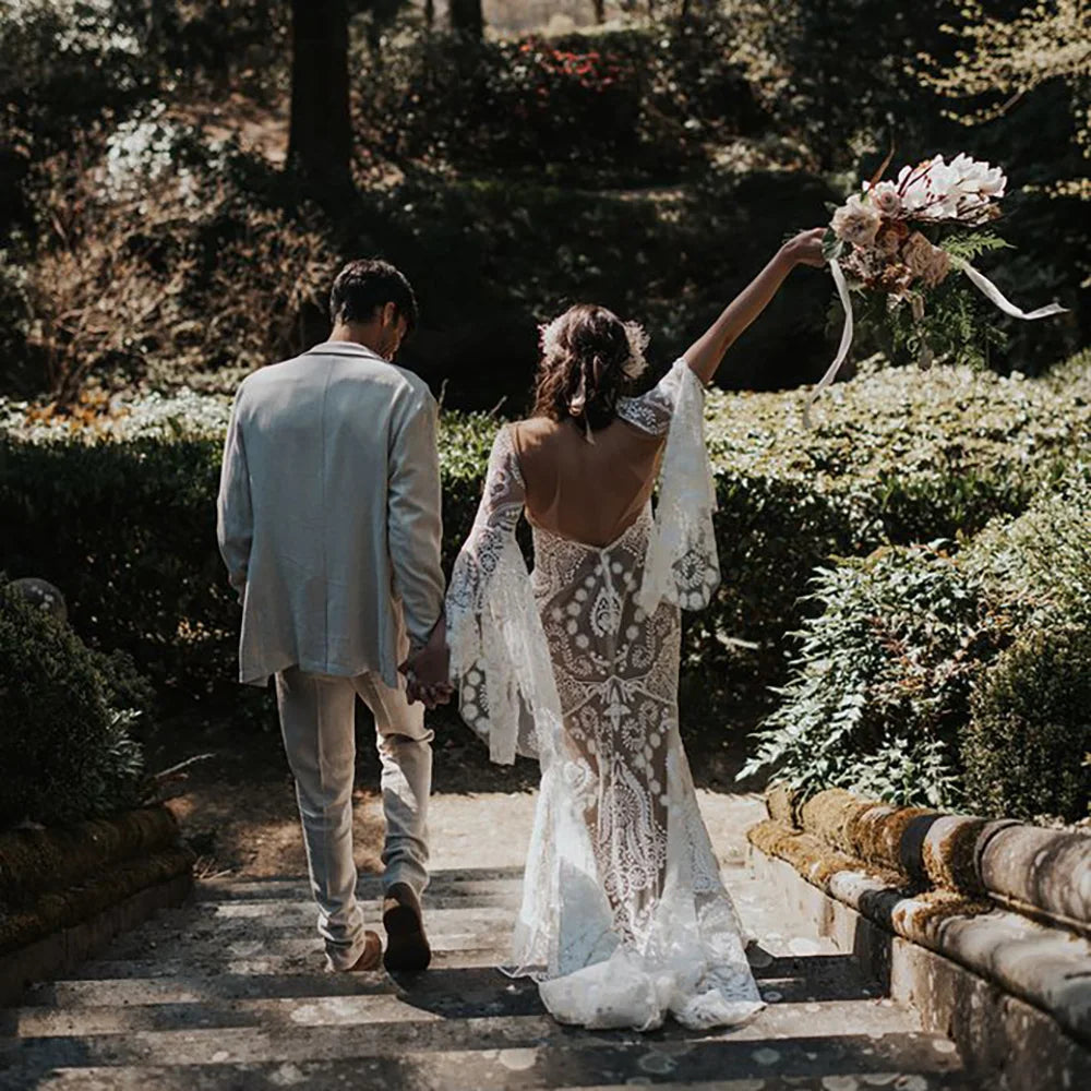 Expertly crafted for the modern and elegant bride, the Robe Anaise features delicate lace detailing and a sleek, form-fitting silhouette. Its long batwing sleeves and high neck add a touch of bohemian flair, while the custom made double slip with slit ensures comfort and movement on the big day. Complete your bridal look with this two-piece, backless sheath gown.