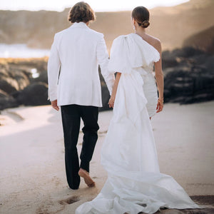 Elevate your wedding look with Robe Elinor. This one-shoulder taffeta dress boasts a chic and elegant design, perfect for a beach wedding. The ruched detailing flatters every curve, while the large bow train adds a touch of sophistication. With its above-knee length, this dress is the epitome of simple yet stylish bridal gowns.